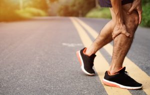 Difference Between A Rupture And A Tear; Sport injury. Accident concept,Young fitness man holding his sports leg injury, after running and exercise outside in summer.