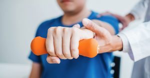 Physiotherapist man giving exercise with dumbbell treatment About Arm and Shoulder of athlete male patient Physical therapy concept; blog: do I really need physical therapy?