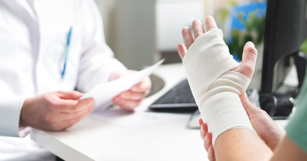 Injured patient showing doctor broken wrist and arm with bandage in hospital office or emergency room. Sprain, stress fracture or repetitive strain injury in hand. Nurse helping customer. First aid; blog: common hand disorders and their treatments