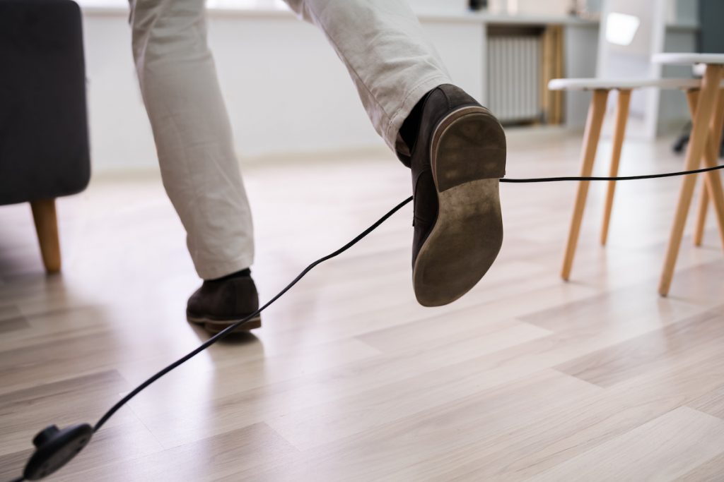 Close-up Of A Man Legs Stumbling With An Electrical Cord At Home; blog: 4 Most Common Trip and Fall Injuries