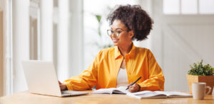 beautiful smiling african american woman  works remotely on laptop from home representing desk workers